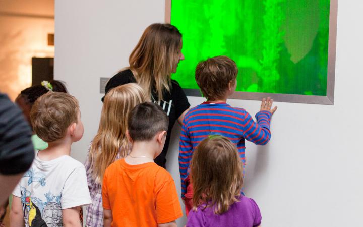 Eine Gruppe von Kindern betrachtet ein grün leuchtendes Bild.