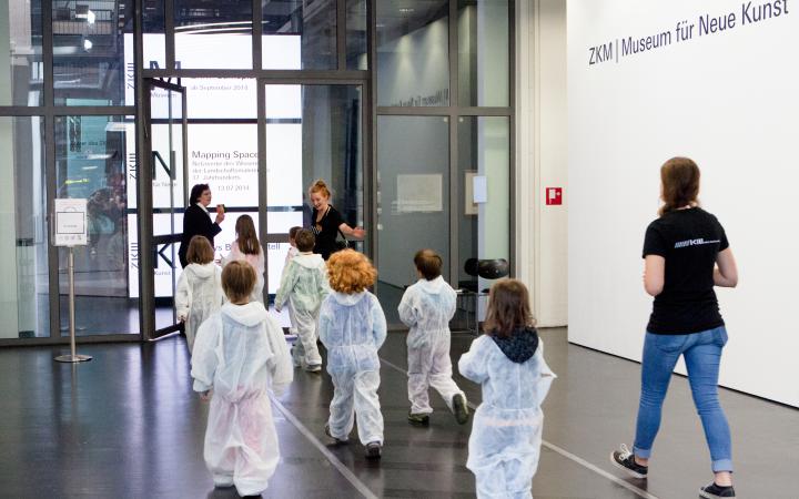 Kids in white overalls entering the Museum für Neue Kunst