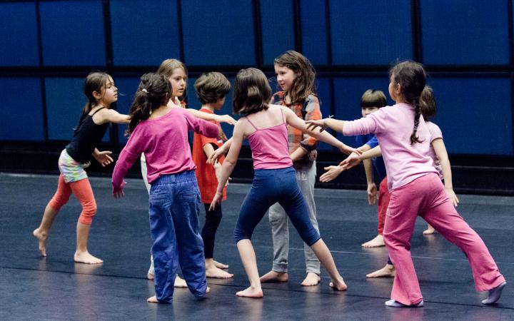 A group of kids in a dance-workshop is standing in a loose circle formation.