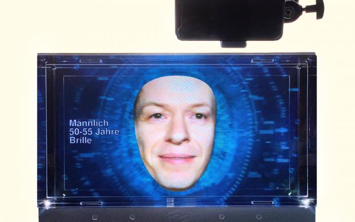 A small screen shows a face against a blue background.