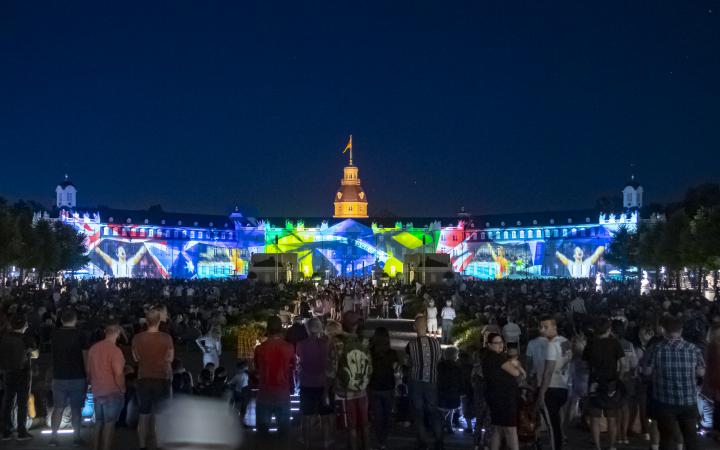 Impressionen aus Sportwettkämpfen wie der Olympiage zeigen sich in einer dynamischen Lichtershow auf der Fassader des Karlsruher Schlosses.