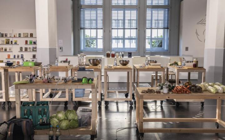 In der ZKM-Ausstellung »Critical Zones« stehen Holztische mit Lebensmitteln und Küchenutensilien.