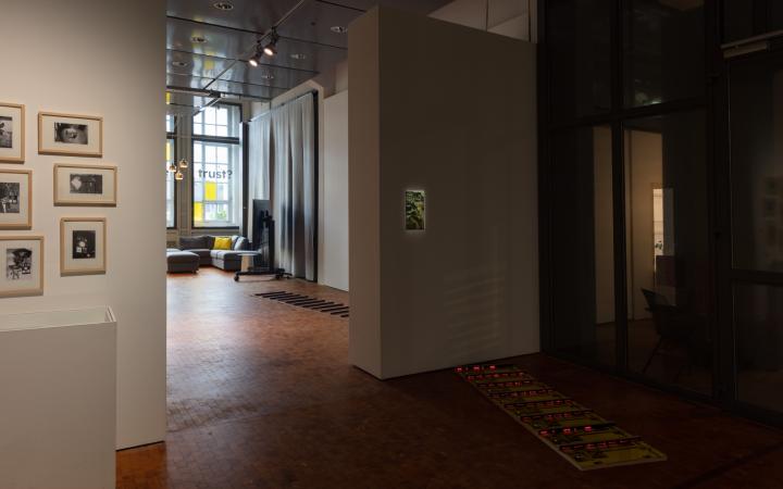 Blick in die Ausstellung auf das Werk »Patterns of Heat« mit am Boden platzierten verspiegelten Platten, rot leuchtenden Streben und einer beleuchteten, an der Wand hängenden Abbildung einer Landschaft