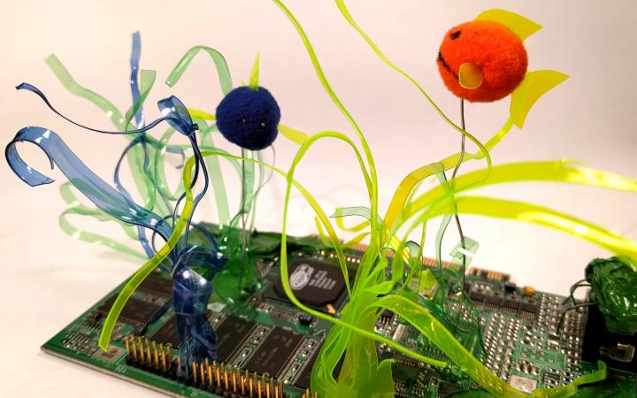 There are flowers made out of colourful plastic bottles soldered to a circuit board.