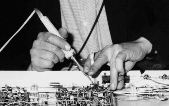 Two male hands can be seen. In one of them a cigarette. The man is fiddling around with electronic works.