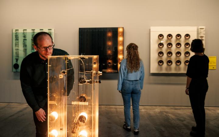 Zu sehen sind drei Personen in der Ausstellung »Walter Giers. Electronic Art«
