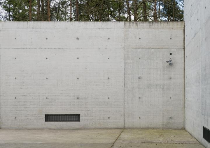 Eine Betonmauer mit einer Lüftung links und einer Überwachungskamera rechts oben