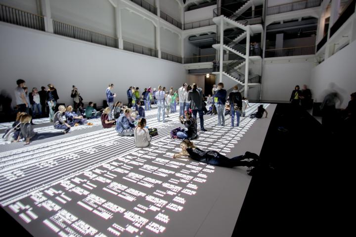 People sitting, lying and standing on a huge projection
