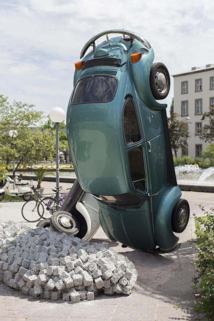 A green VW beetle standing on its head