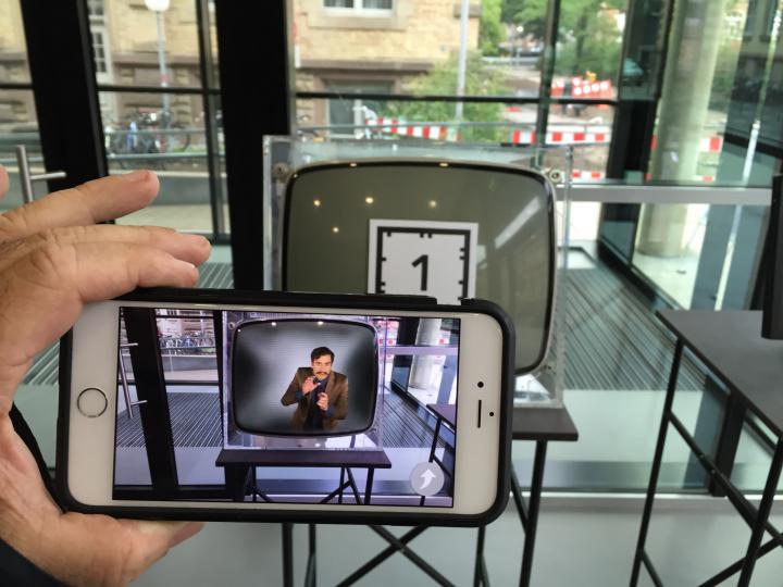 A smartphone is helt to catch the augmented reality marker glued on a cathode ray tube TV. 