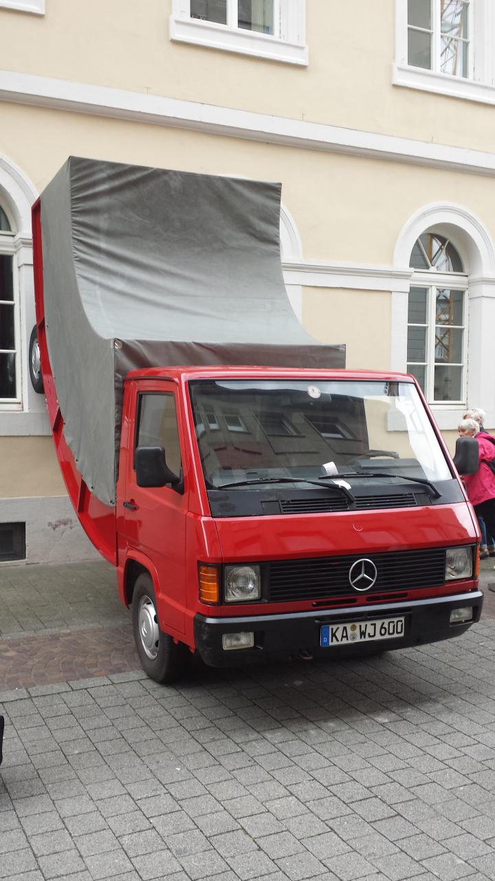 Ein roter Truck, dessen Hinterräder an der Wand stehen.