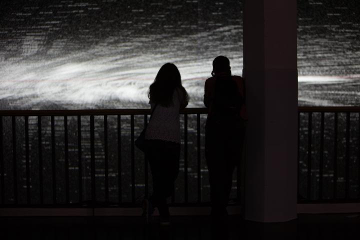 Shadows of two people in front of a black and white projection
