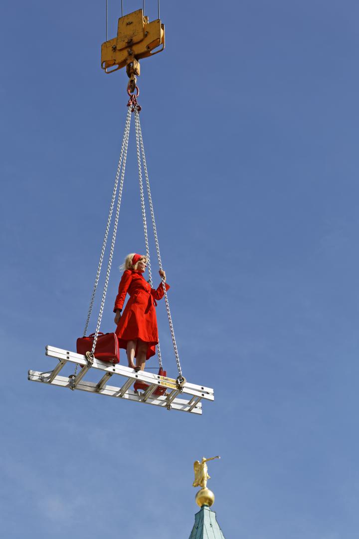 A blonde woman in a red dress on a floating ladder