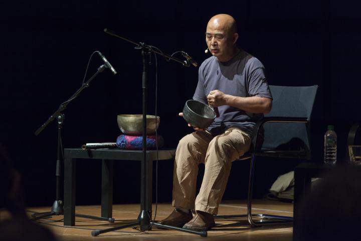 A man with a singing bowl on stage