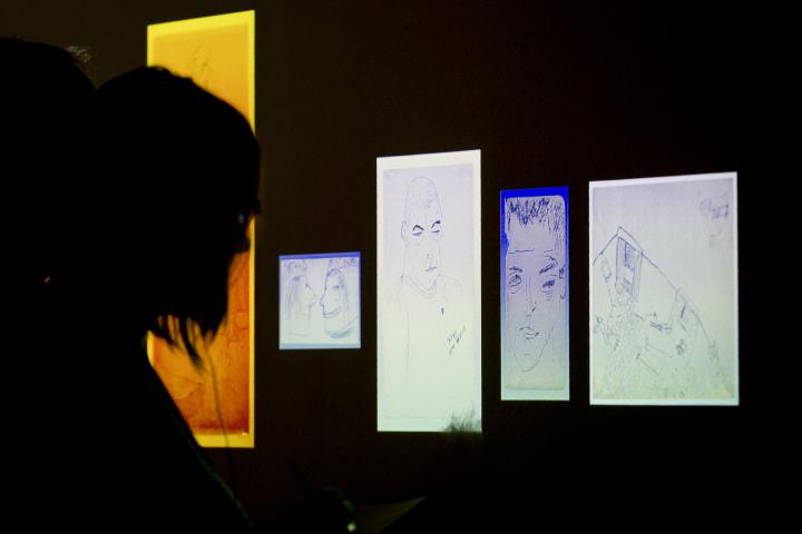 Eine Person blickt im Dunkeln auf beleuchtete Zeichnungen