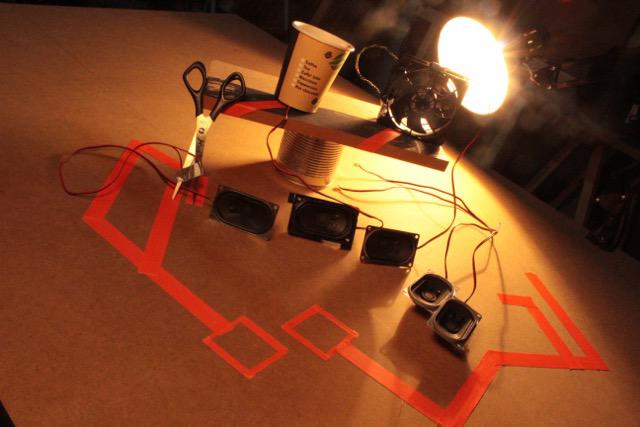 Verschiedene Lautsprecherboxen werden von einer Schreibtischlampe beleuchtet.