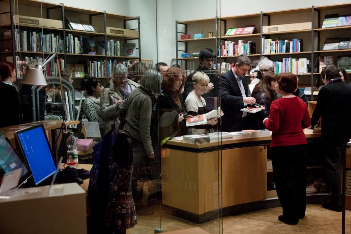 People stand in front of a desk full of books