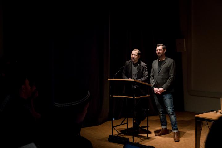 Zwei Personen stehen vor einem Pult und sprechen zum Publikum
