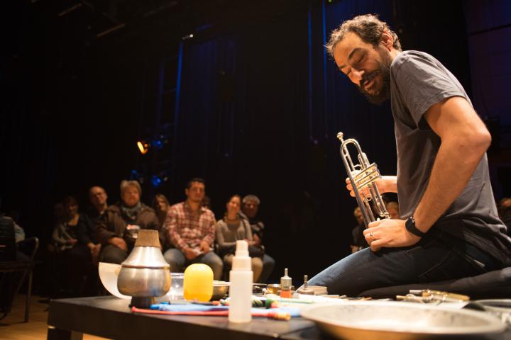 A man sits on the ground and presents different instruments