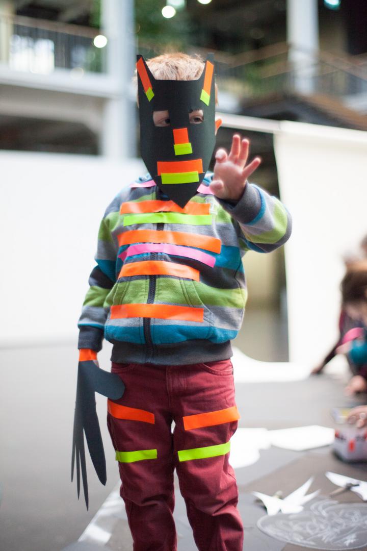 A boy with a homemade mask and various strips on clothing