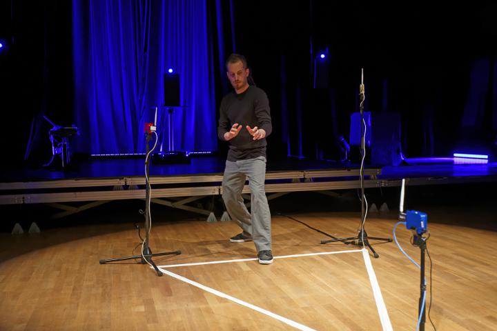 A man stands in a with tape drawn triangle