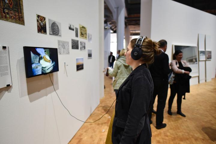 Eine Frau steht mit Kopfhörern vor einem kleinen Bildschirm