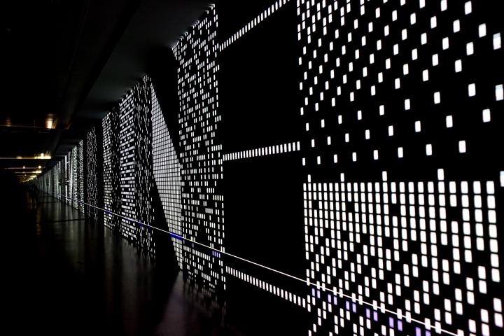 Eine schwarze Leinwand mit gepunkteten LED-Strukturen, die sich scheinbar bis Unendliche erstreckt. 