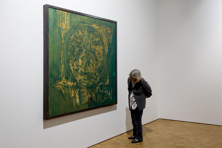 The picture shows a woman in front of a painting by Markus Lüperz
