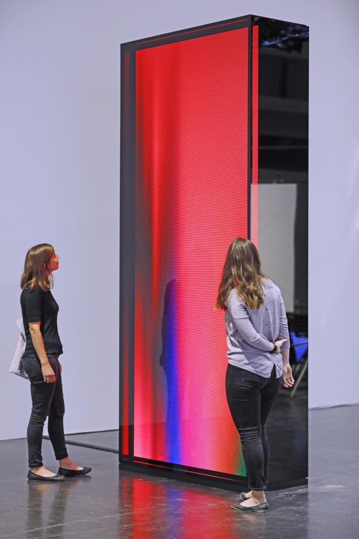Visitors in front of a 3.5m high reddish "cosmic" light sculpture.