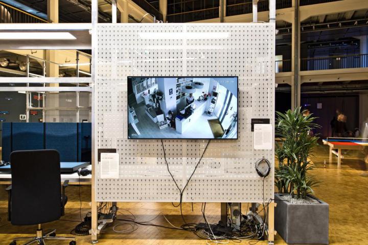Die Ausstellungsansicht zeigt ein Bildschirm mit einer Raumaufnahme an einer Stellwand
