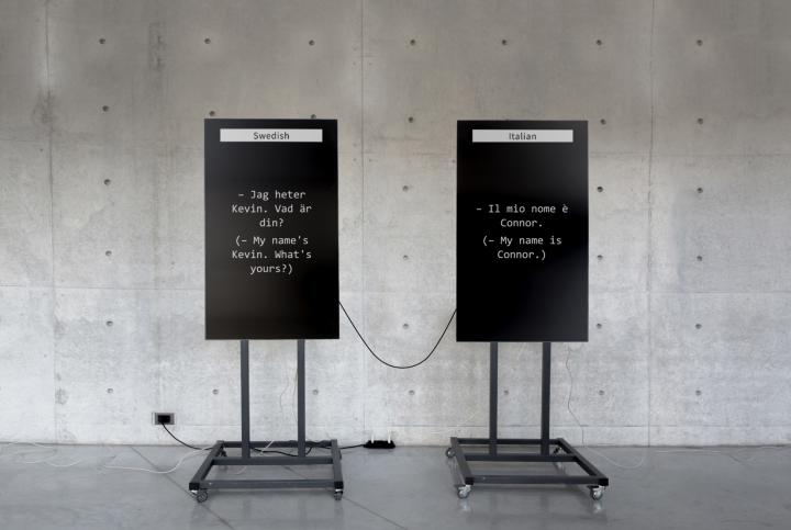 The picture shows two large screens: one translates to Swedish and the other to Italian