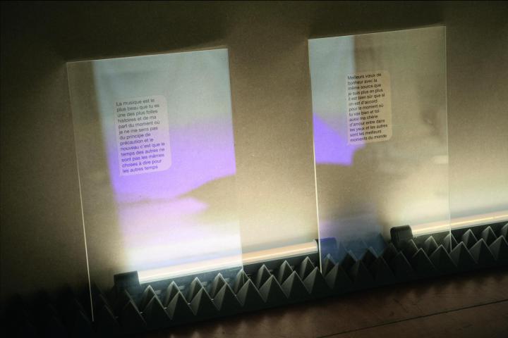 Zwei transparente Glasplatten sind in Noppenschaumstoff einglassen. Auf ihnen französische Texte in Sprechblasformen zu sehen. 