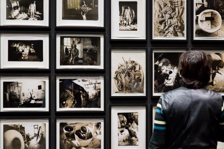 Das Foto zeigt die Rückenansicht eines Mannes vor mehreren Schwarz-Weiß-Fotografien Tambellinis