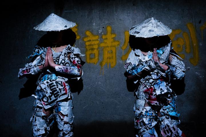 The Duo group A in front of a grey wall with yellow Japanese characters
