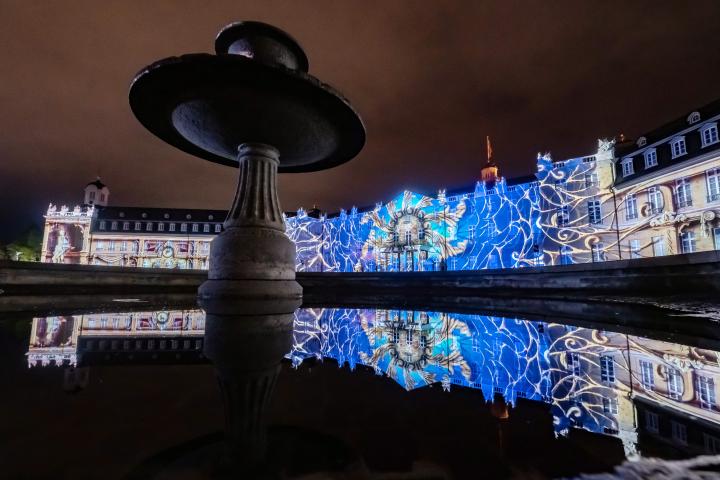 Photo of a colorful projection mapping at night on the baroque Karlsruhe castle.