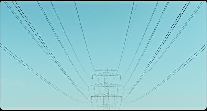 Das Bild zeigt einen Strommast vor einem türkisblauen Himmel. 
