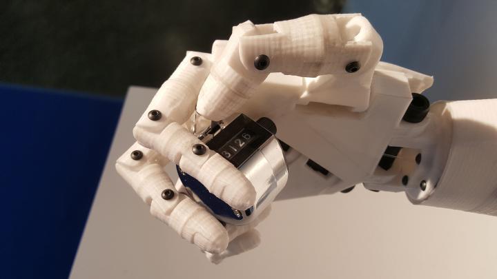 Das Foto zeigt eine weiße Roboterhand die einen Clicker umschlossen hält.