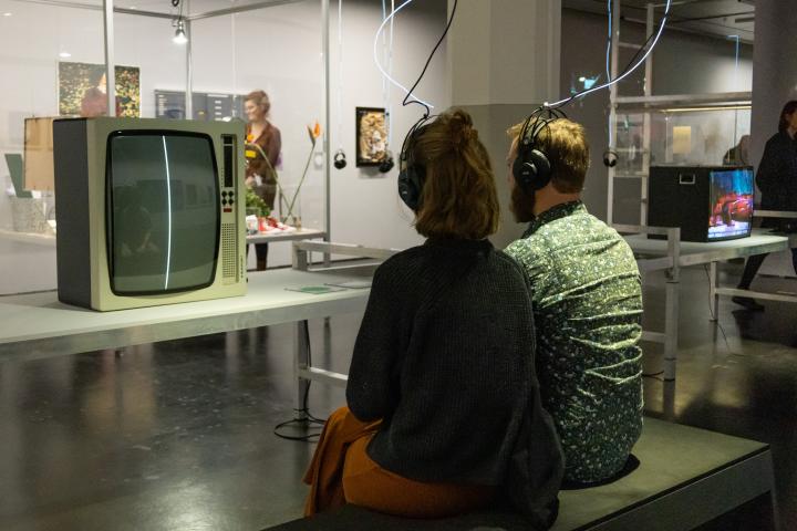 Exhibition view »Matter. Non-Matter. Anti-Matter« at ZKM | Center for Art and Media Karlsruhe, 2022. You can see two people sitting with their backs to the camera. They wear headphones