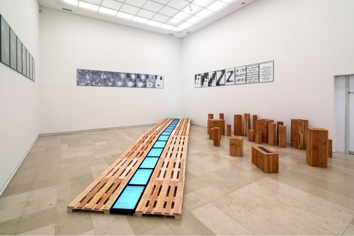 Monochrome screens lie in the middle of a longer row of palettes. On the right are single small blocks. On the walls hang small square posters with abstract motives.