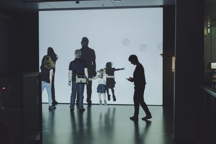 Museum visitors move in front of a canvas with soap bubbles