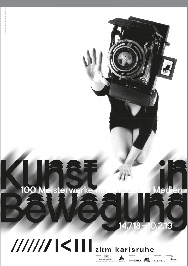 Das Plakat der Ausstellung »Kunst in Bewegung« zeigt eine knieende Frau, deren Kopf von einer überdimensionalen Kamera verdeckt ist. 