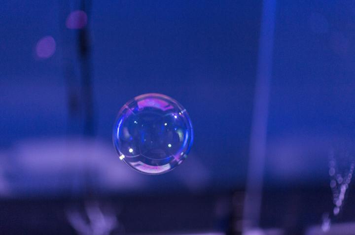 A soap bubble against a violet, dark background. 