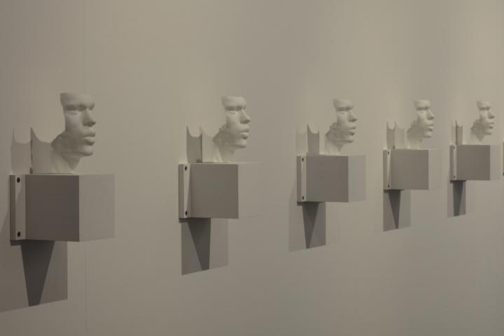 Mehrer Büsten – 3D-Drucke der Stimmbänder der Künstler – hängen nebeneinander an einer Wand. 