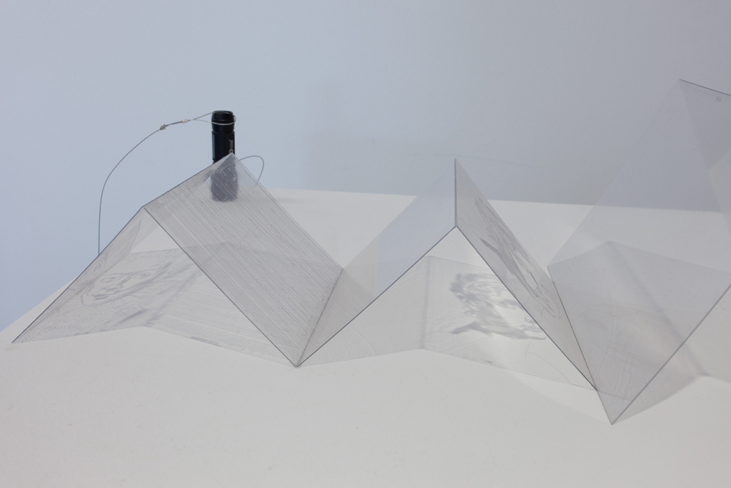 Ein zu Pyramiden gefaltetes Stück Plastik, auf dem ein Gesicht zu sehen ist.