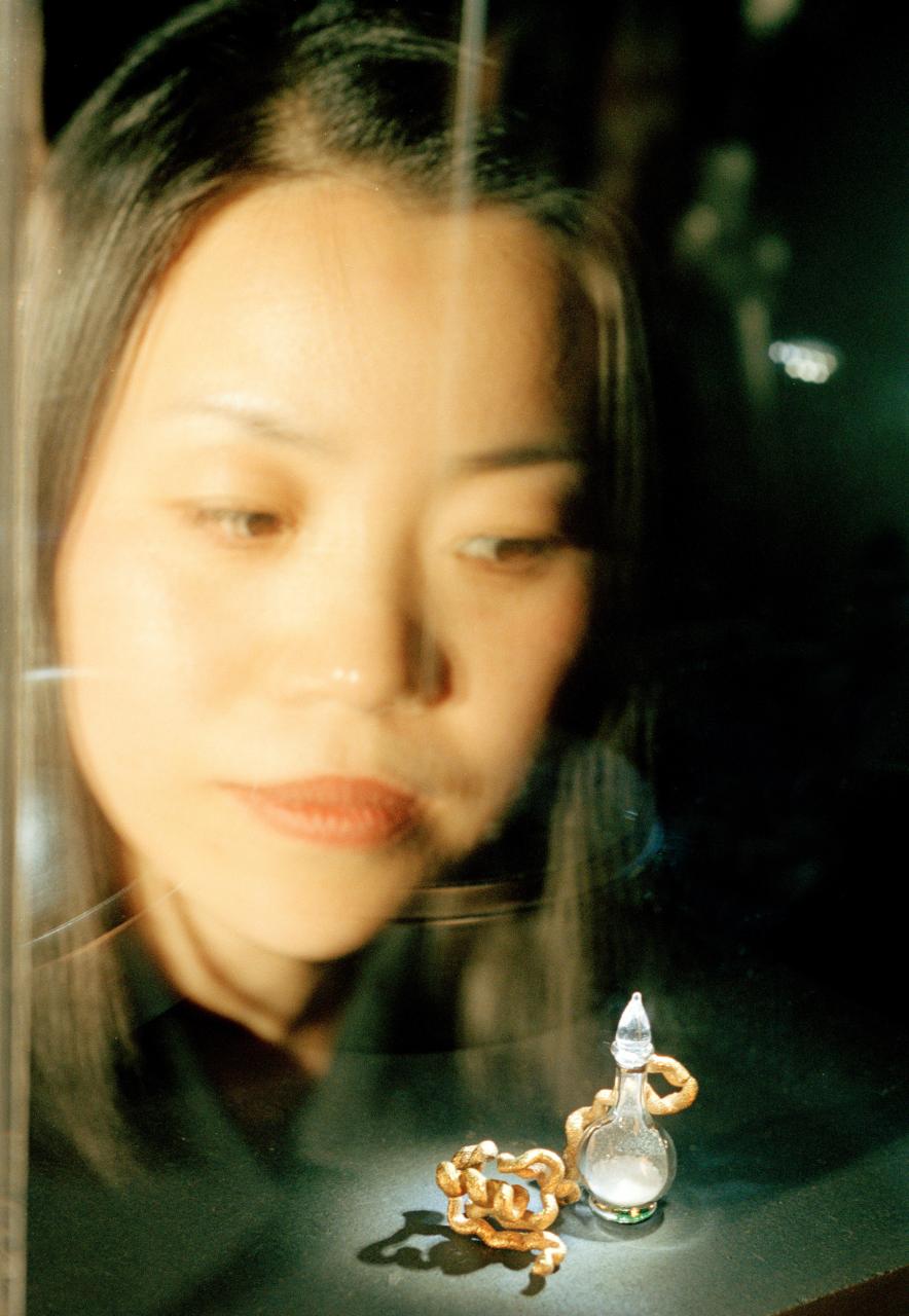 Eine Frau betrachtet durch eine Scheibe zwei kleine erleuchtete Objekte