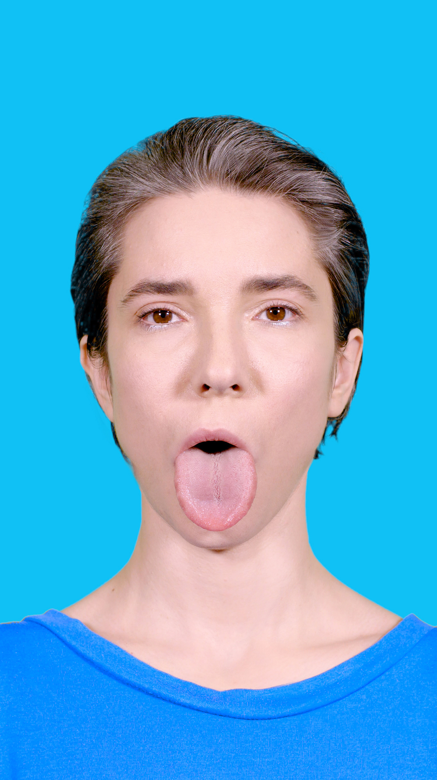 The screenshot shows a woman sticking her tongue frontally into the camera.