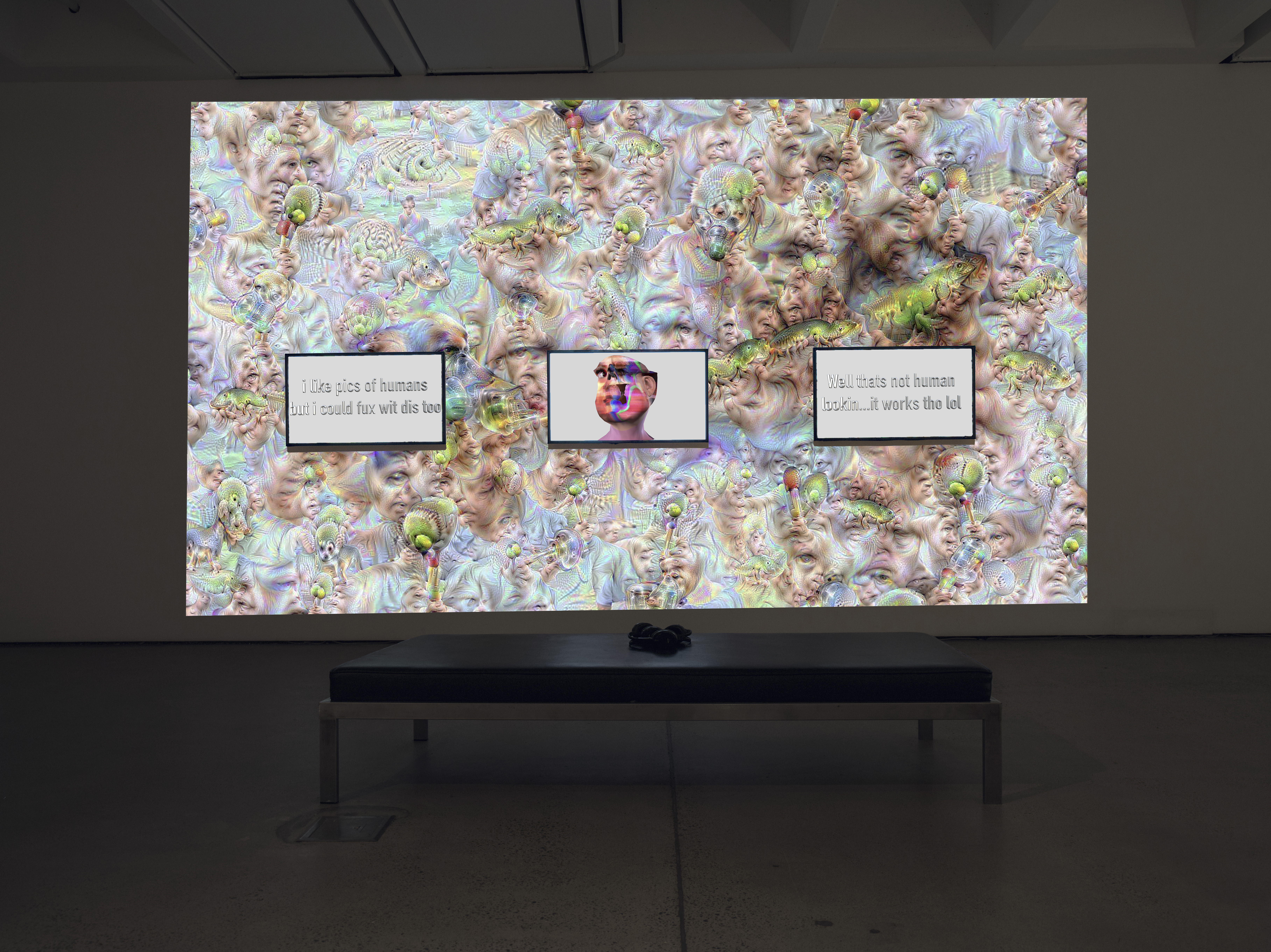 The photo shows an exhibition view of the work »im here to learn so :))))))«. Shown is a large screen in the background and three screens in the foreground. They show a psychedelic cosmos and the chatbot Tay.