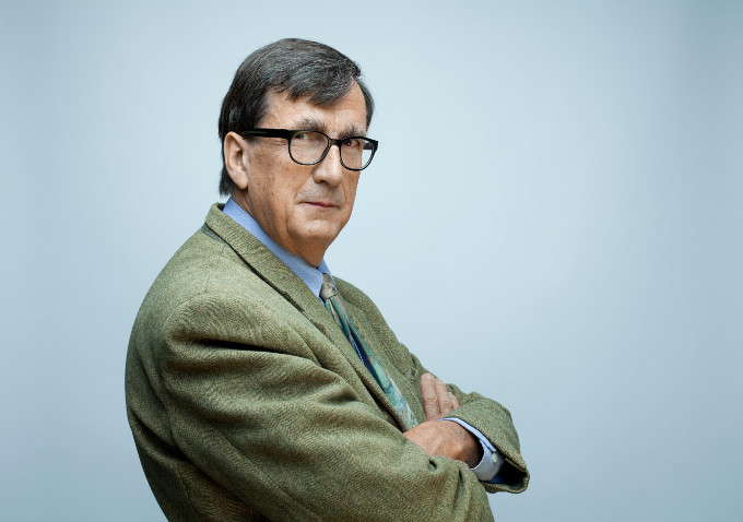 Ein Portrait von Bruno Latour. Er steht leicht seitlich zur Kamera, die Arme verschränkt.