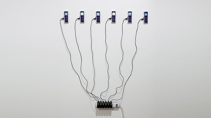 Wandinstallation aus sechs mobilen Geräten an Ladekabeln
