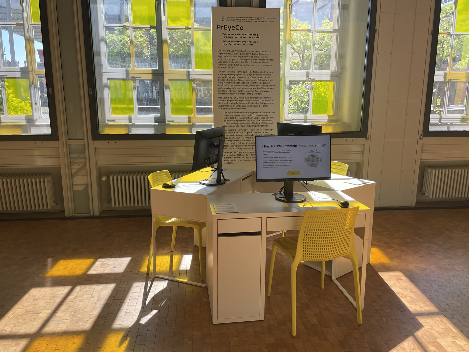 Ausstellungsansicht vom Werk PrEyeCo; drei Schreibtische mit Computern und gelben Stühlen